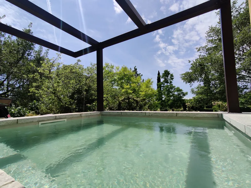 Bassin de la piscine SPA à l’eau calme, sous la pergola ouverte