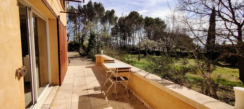 Table et chaises sur la terrasse longeant la façade du Mazet, face au jardin